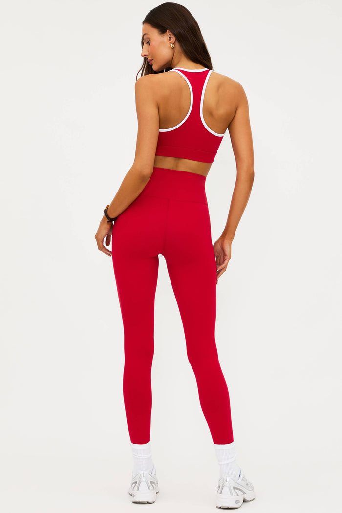 Person wearing a red sports bra and leggings set on a white background