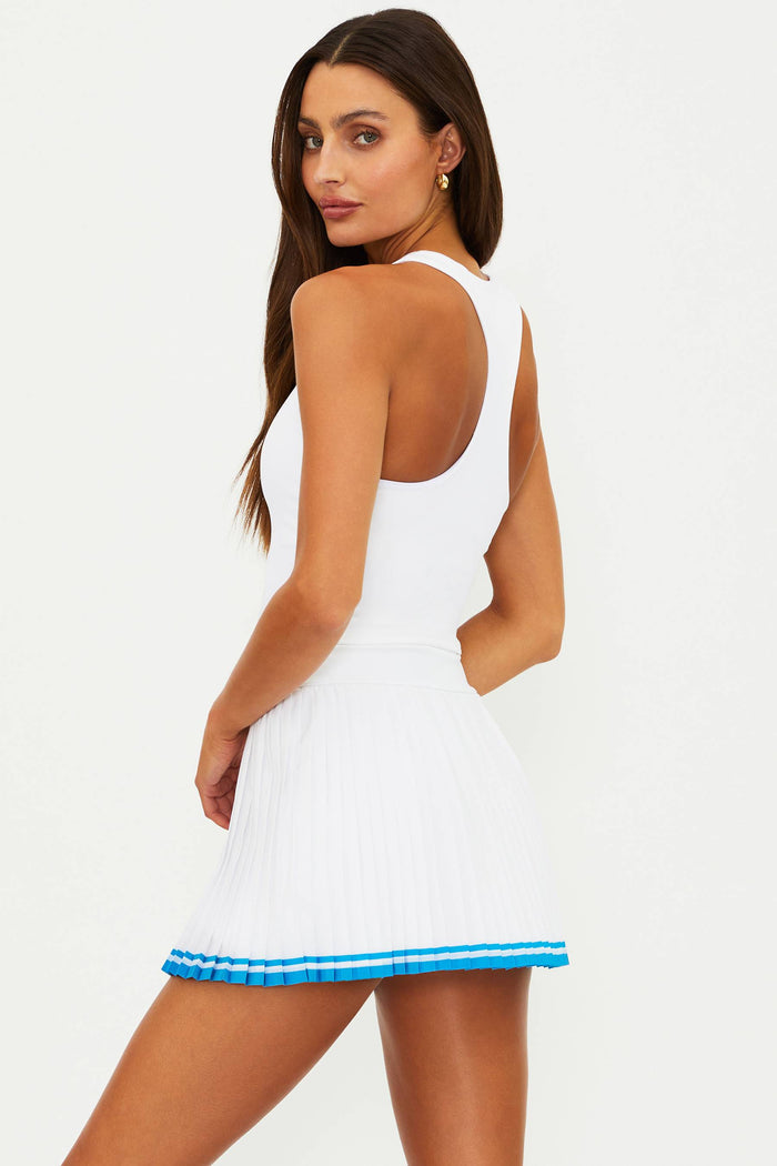 Woman wearing a white dress with blue trim on a plain background