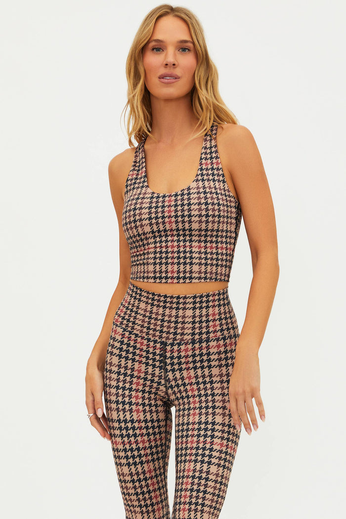 Woman wearing a houndstooth patterned outfit on a plain background