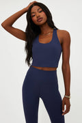 Woman wearing a navy blue athletic outfit on a white background
