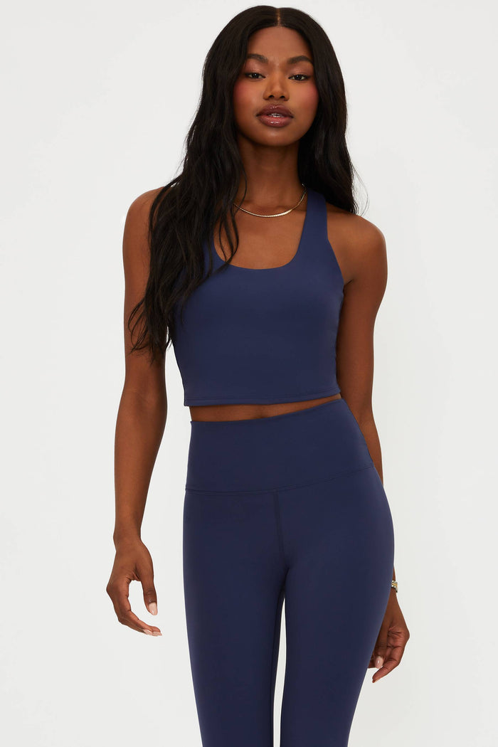 Woman wearing a navy blue athletic outfit on a white background