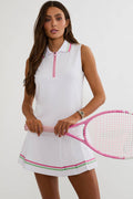 Woman in a white tennis dress with pink accents holding a pink tennis racket on a white background